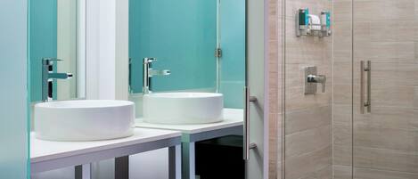 Un baño moderno con cabina de ducha de vidrio, un lavamanos blanco y un inodoro.