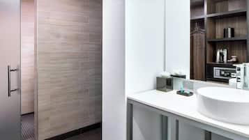 A modern bathroom with a large mirror, a white sink, and a shower area with wooden tiles.