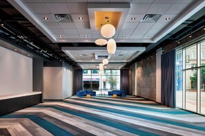 A spacious hotel lobby with a modern design, featuring a long reception area, large windows, and a patterned carpet. - Aloft by Marriott Fort Worth Downtown (Fort Worth)