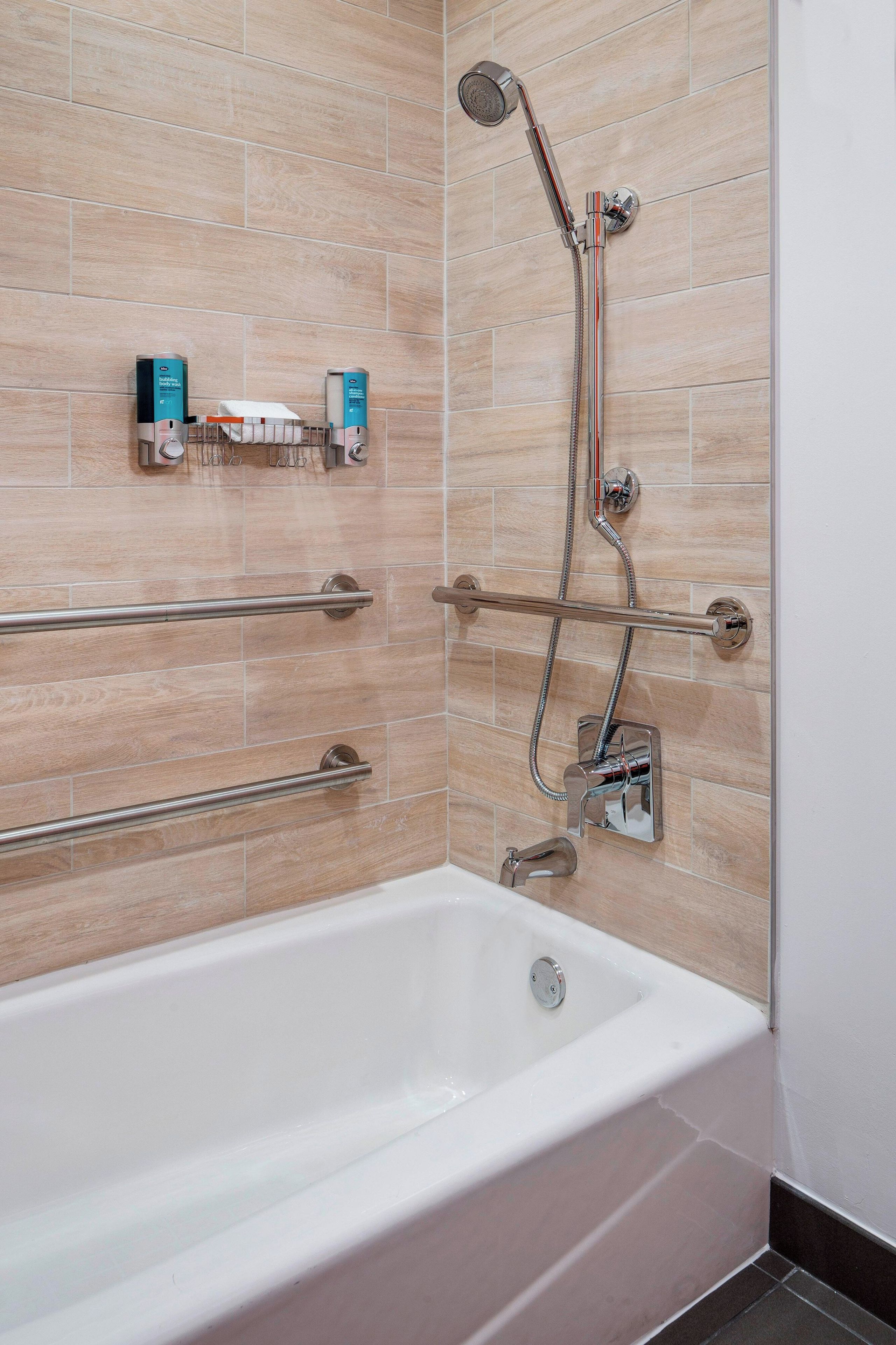Un baño moderno con bañera, ducha y barras de apoyo.