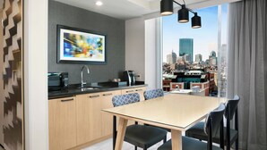 A modern kitchen with a city view, a dining area with a table and chairs, and a microwave on the counter. - Courtyard by Marriott Boston Downtown/North Station (Boston)