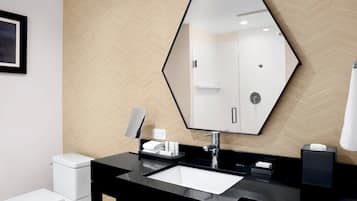 Un baño moderno con un lavabo negro, un espejo grande y un inodoro.