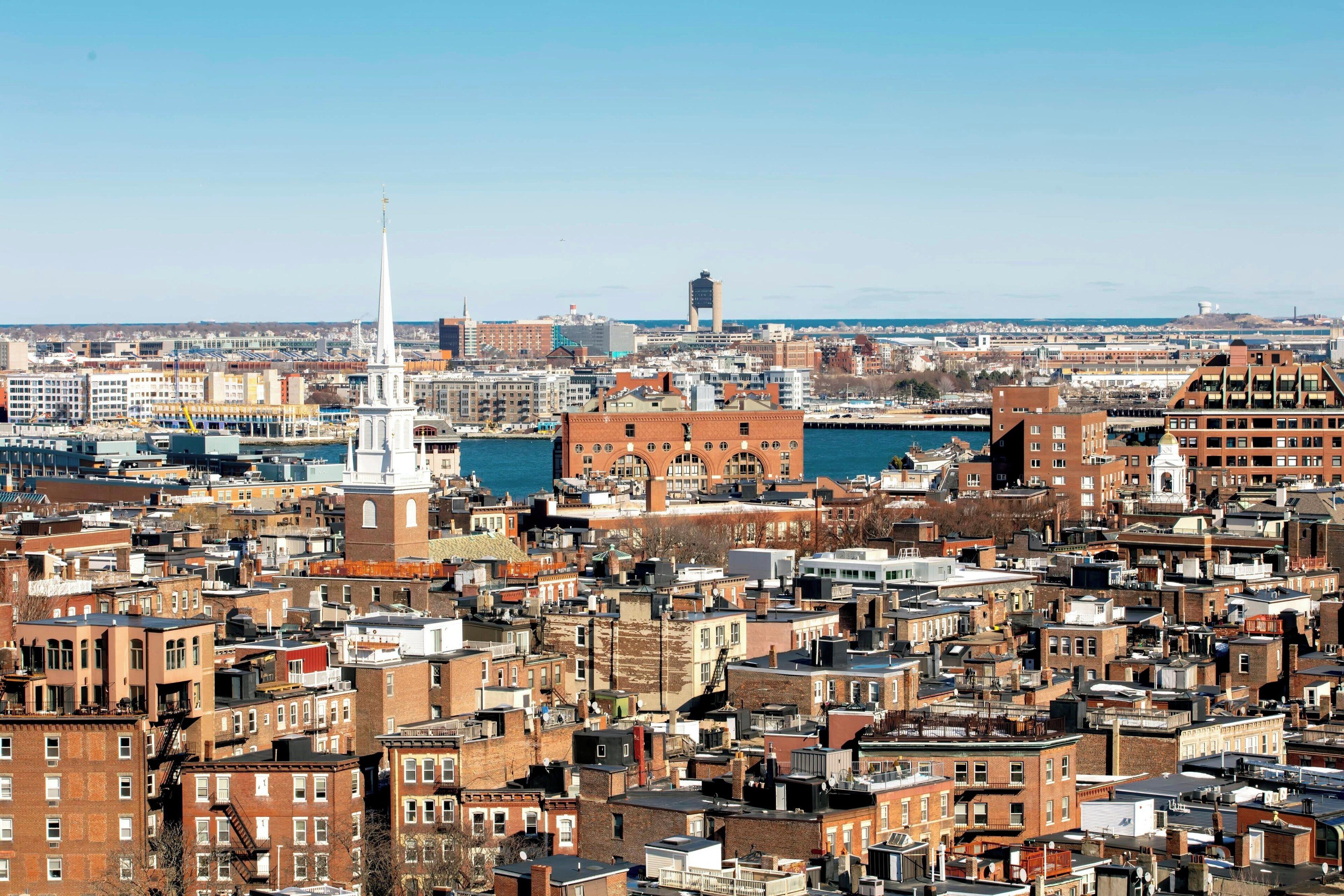 A densely packed urban area with various building types, including a prominent white spire and a large water tower in the background.