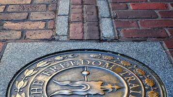 Eine Metalltafel mit der Aufschrift 'The Freedom Trail' und 'Boston' auf einem Backsteinpflaster.
