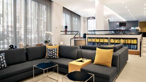 A modern living room with a sofa, coffee table, and bookshelves. - Courtyard by Marriott Boston Downtown/North Station (Boston)
