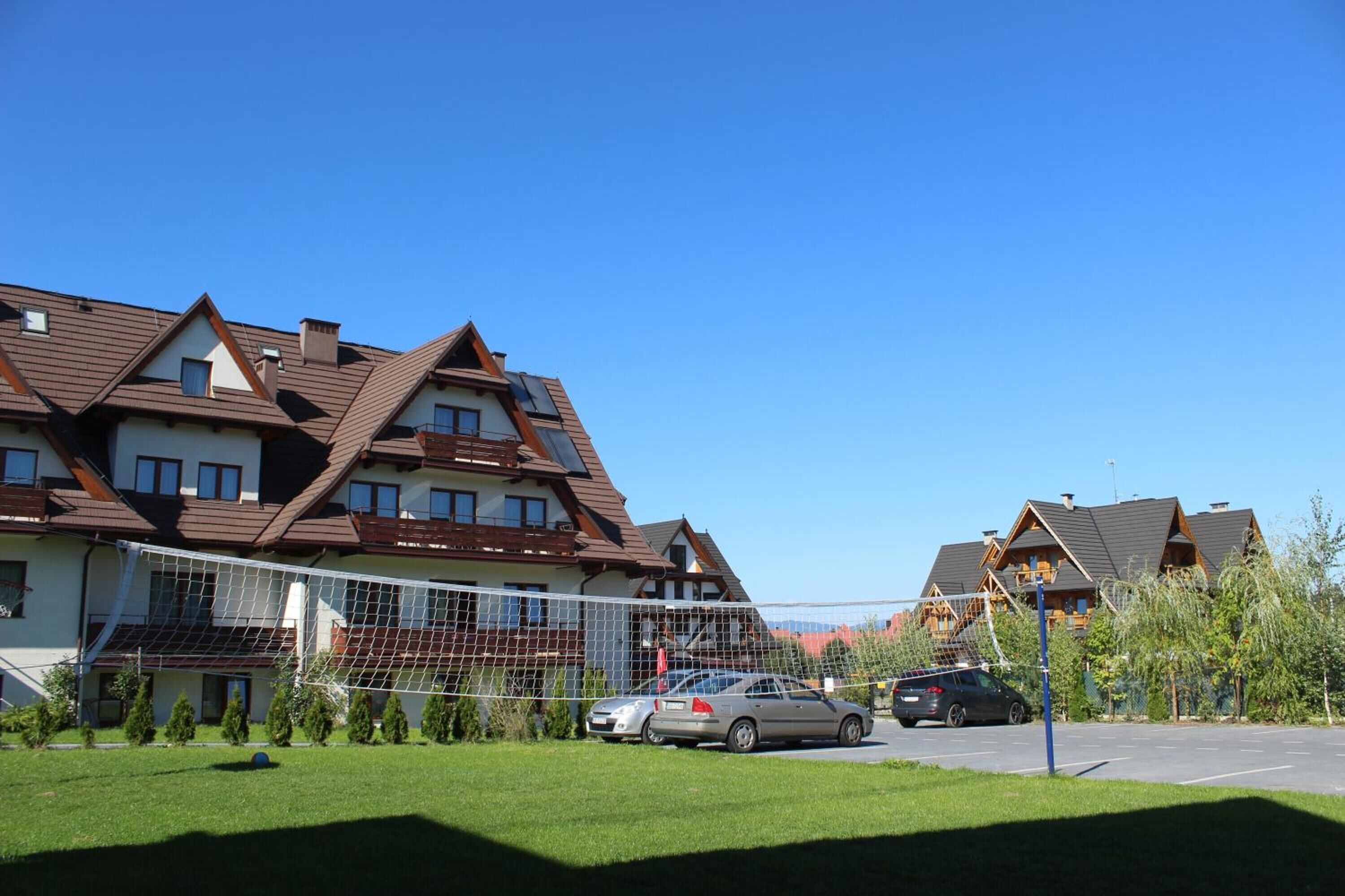 A residential area with houses, a volleyball net, and parked cars.