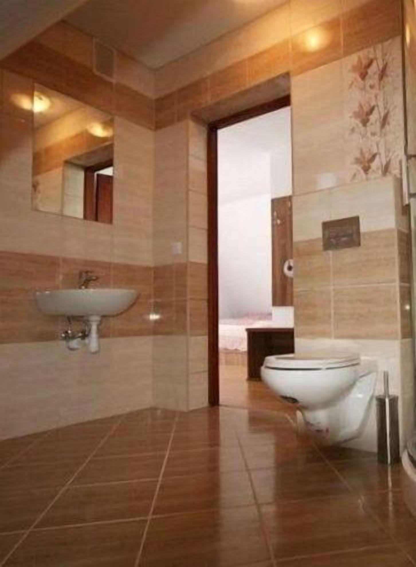 A modern bathroom with a sink, toilet, and a mirror.