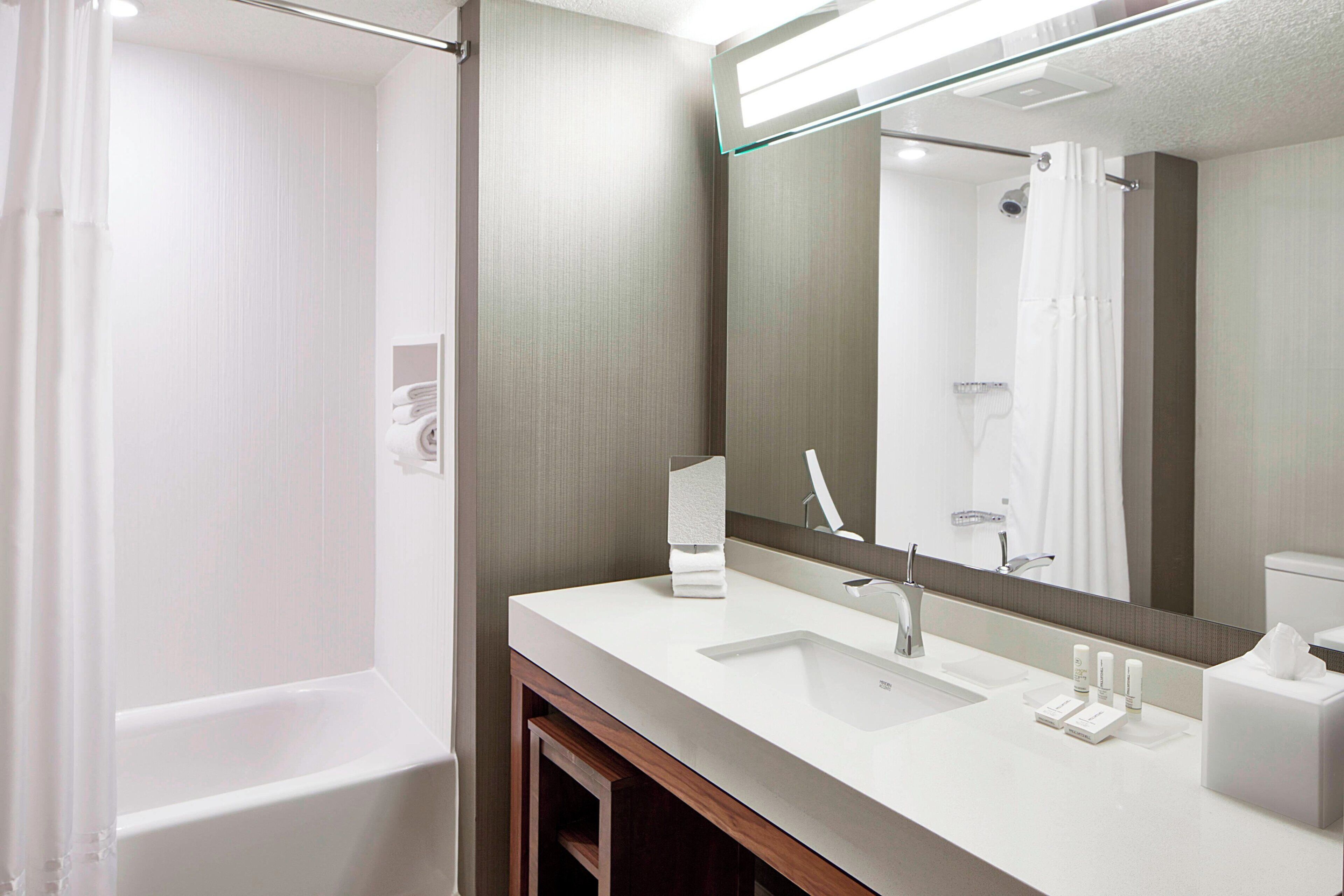 A modern bathroom with a bathtub, a sink, a mirror, and a towel rack.
