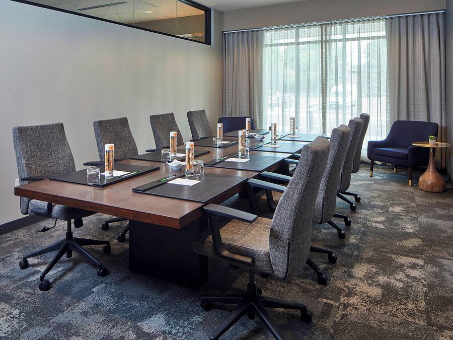 A conference room with a long table, multiple chairs, and a small side table with a plant.