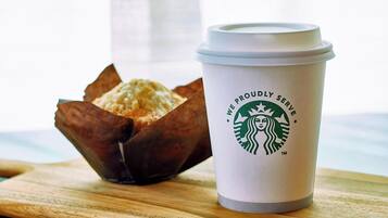 Una taza de Starbucks con un muffin sobre una tabla de madera.