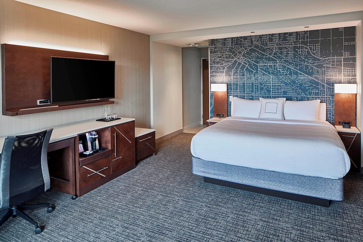 Una habitación de hotel con una cama grande, un escritorio con silla, un televisor de pantalla plana y un mapa mural.