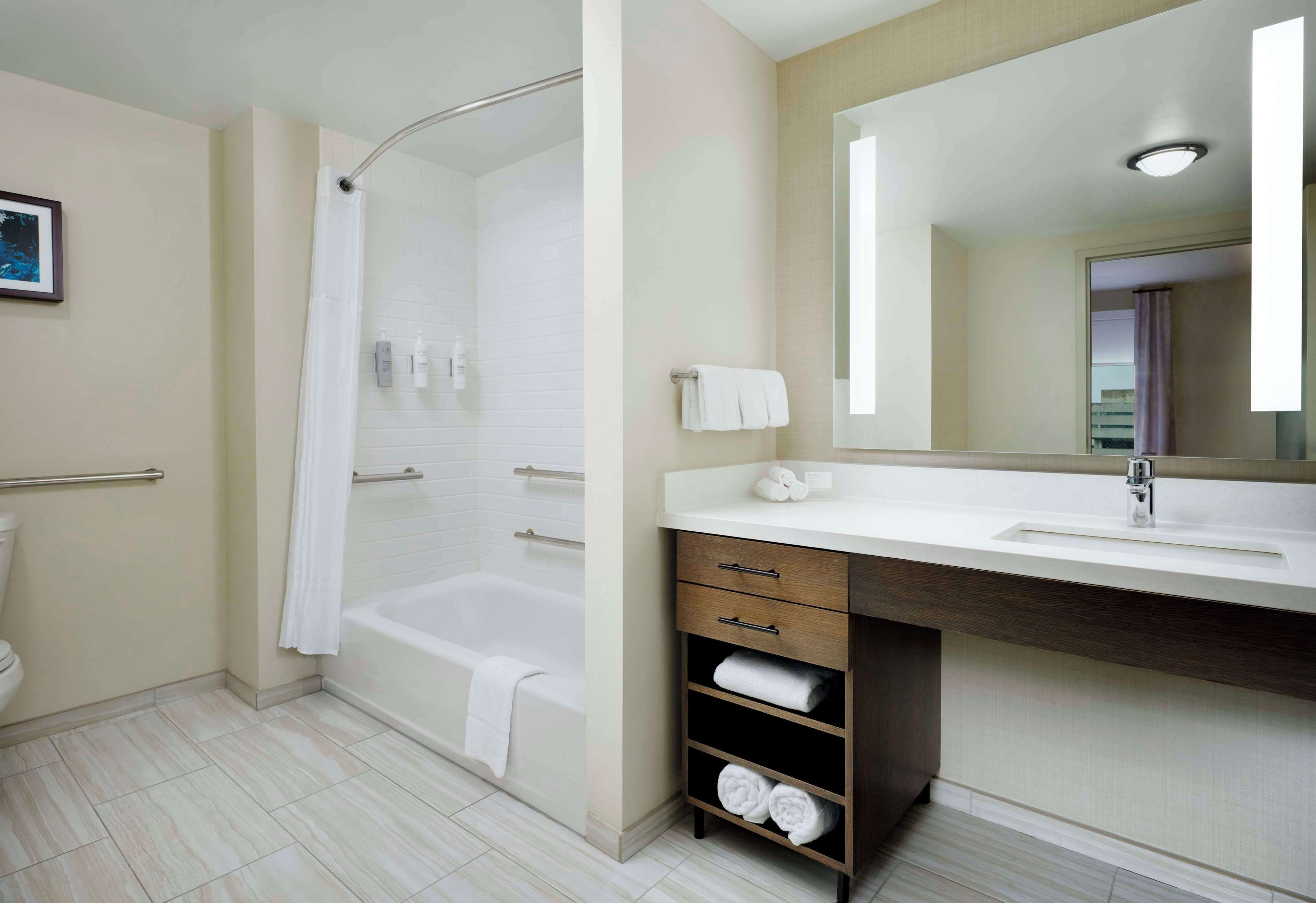 A modern bathroom with a bathtub, a vanity with a mirror, and a toilet.