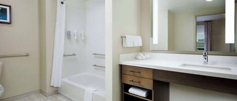 A modern bathroom with a bathtub, a vanity with a mirror, and a toilet.