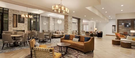 A spacious lobby with a large seating area, a chandelier, and a patterned rug.
