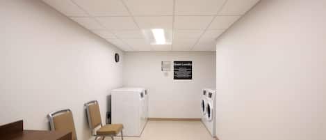 A laundry room with a table, chairs, and two washing machines.