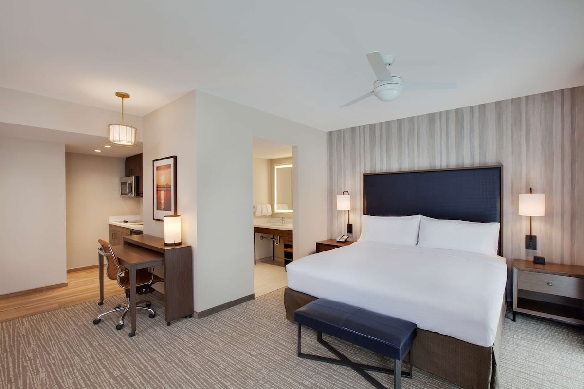 Une chambre d’hôtel équipée d’un lit, d’un bureau, d’une chaise et d’un ventilateur de plafond.