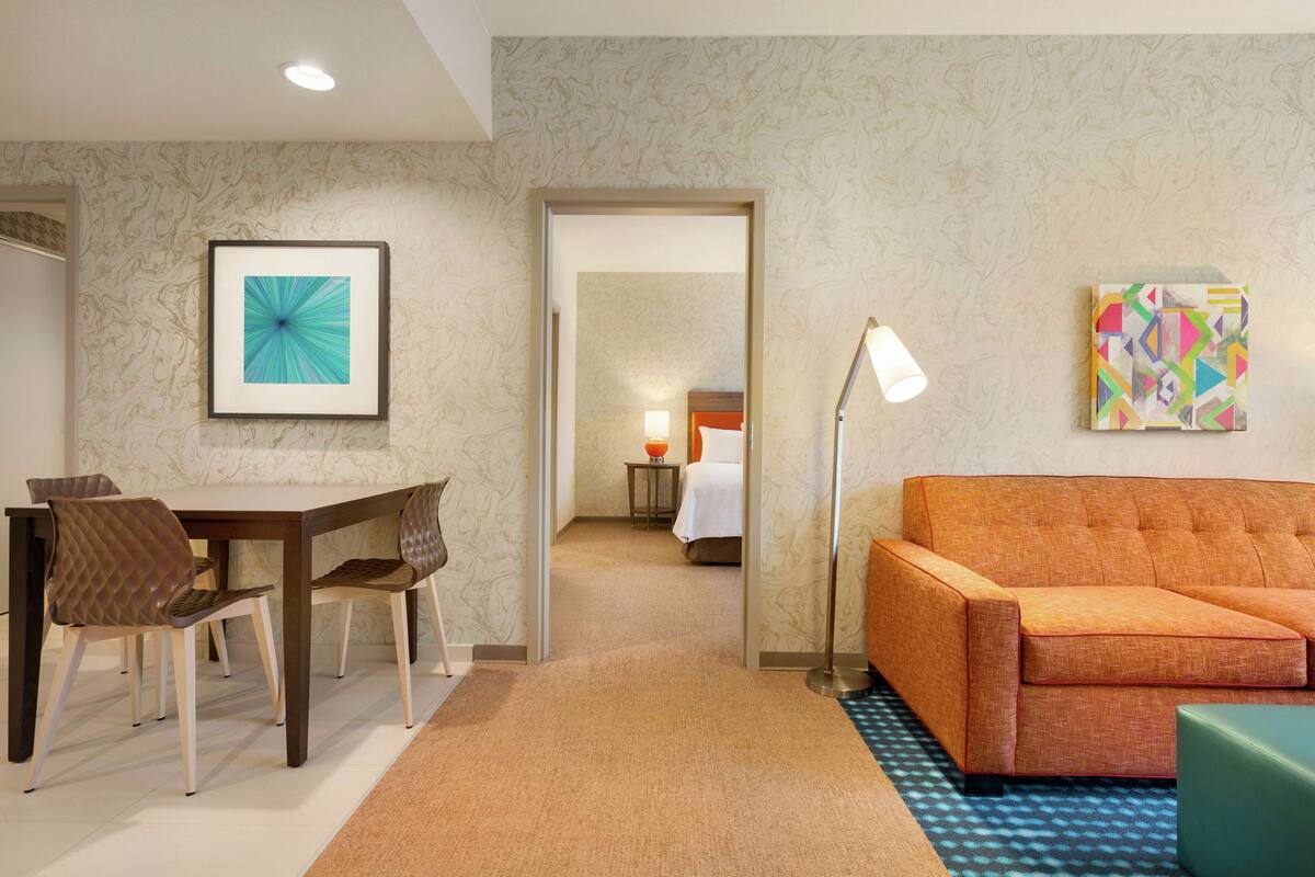 A hotel room with a dining area, a sofa, and a bed.