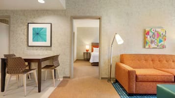 Una camera d'albergo con zona pranzo, divano e letto.