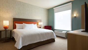 A hotel room with a large bed, two bedside lamps, a red chair, a desk, and a large window.
