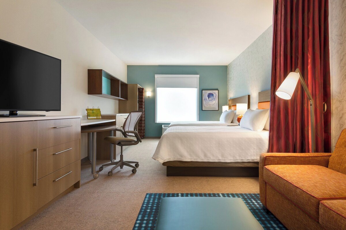 A hotel room with a bed, a desk, a television, and a window.