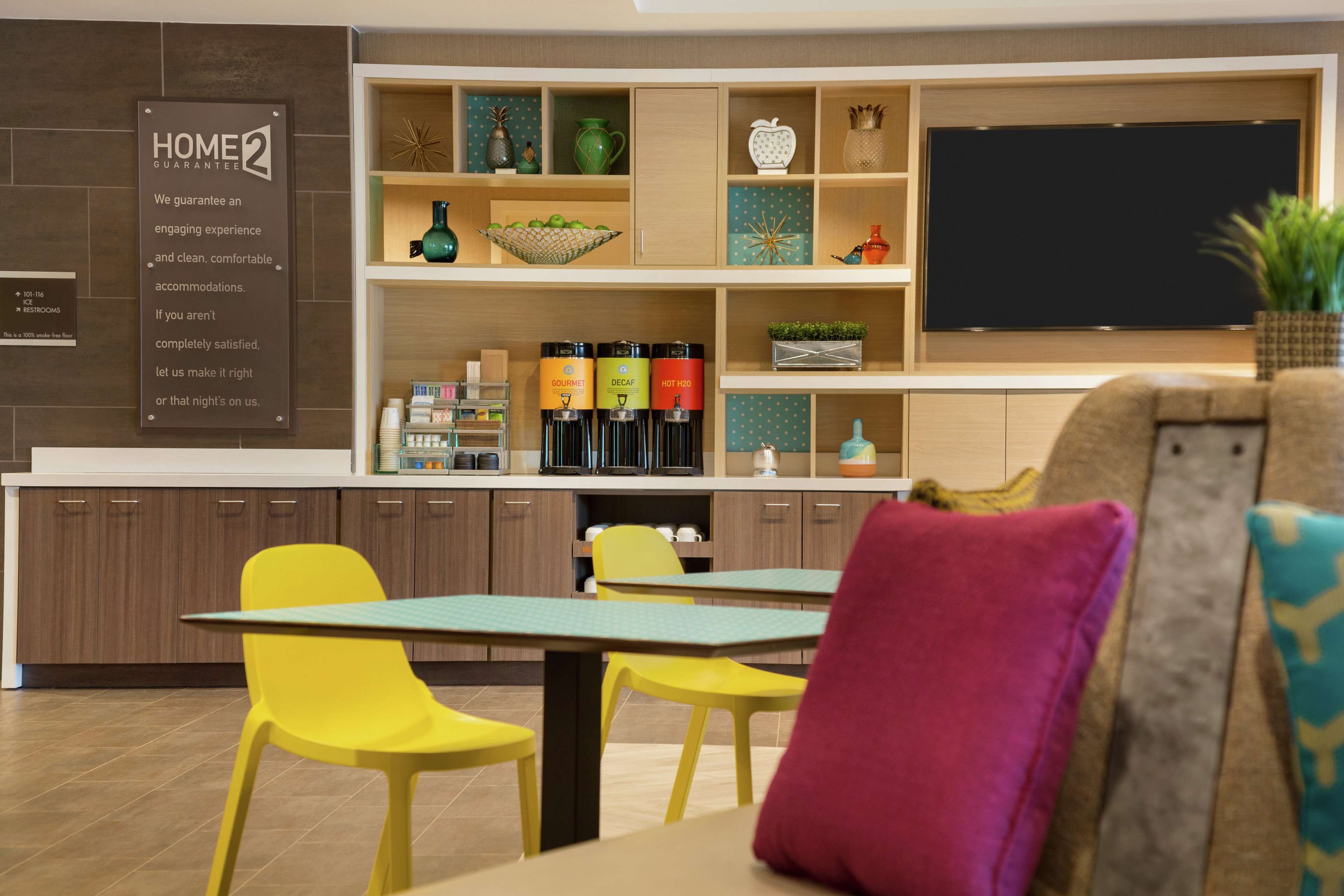 A modern kitchen with yellow chairs, a blackboard, and a sign stating a home guarantee.