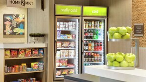 A snack and beverage section with a variety of snacks and drinks, including a display of green apples. - Home2 Suites by Hilton Frederick (Frederick)