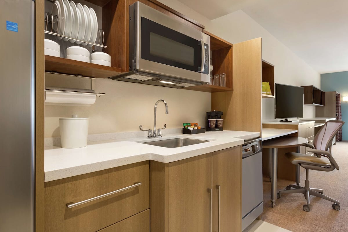 A compact kitchen with a microwave, sink, and cabinets.