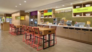 A restaurant with a long counter, red chairs, and a 'Good Morning' sign. - Home2 Suites by Hilton Frederick (Frederick)
