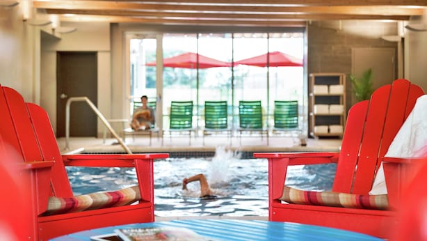 A pool area with red chairs and a person swimming. - Home2 Suites by Hilton Frederick (Frederick)