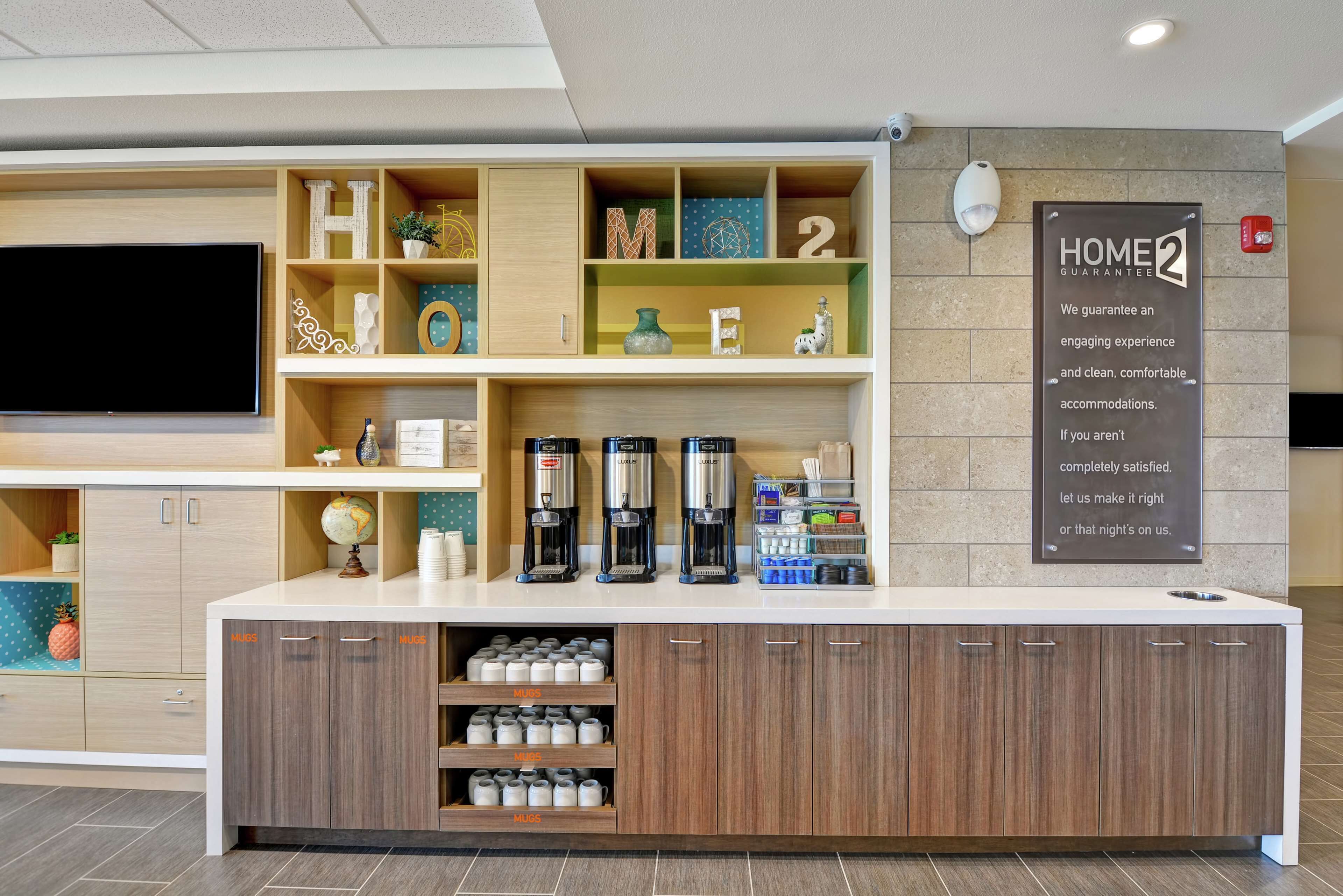 Et hotelreceptionsområde med et fladskærms-tv, kaffestation og et skilt, der angiver en boliggaranti.