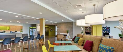 A modern lobby with a reception desk, seating area, and a coffee bar.
