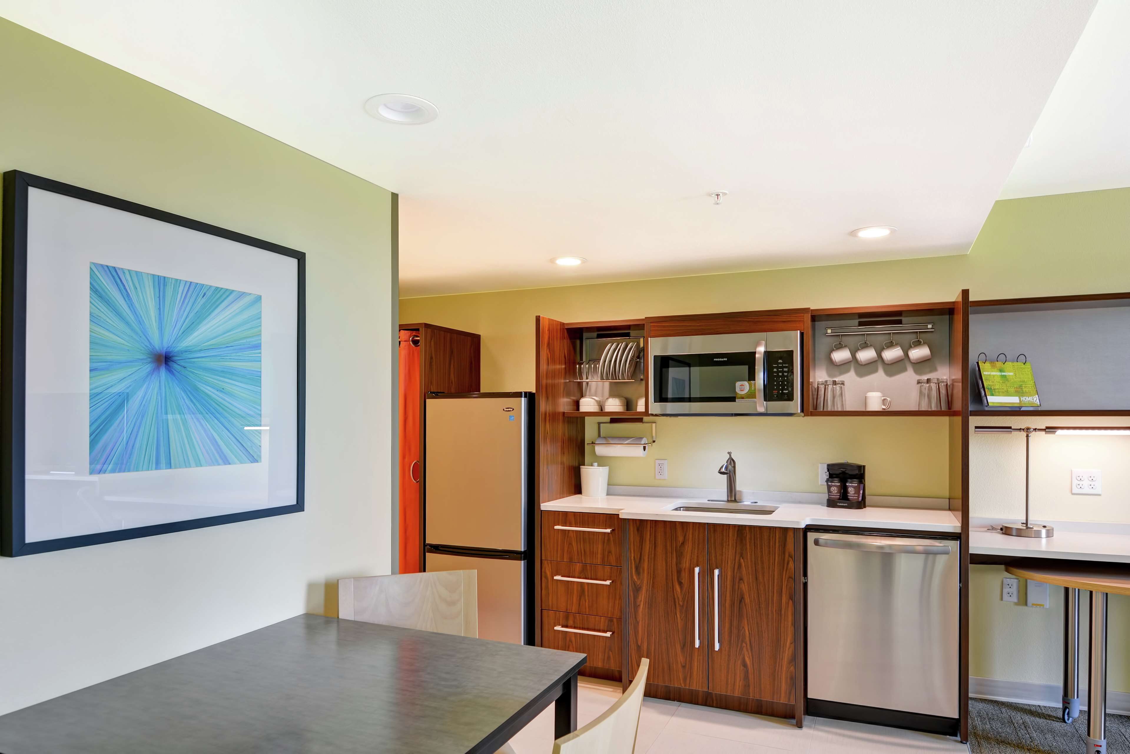 A compact kitchen with wooden cabinets, a refrigerator, a microwave, and a dishwasher.