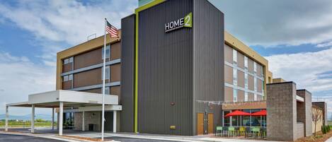 Un hotel moderno con un llamativo letrero de "HOME 2", estacionamiento techado y un área de estar al aire libre.