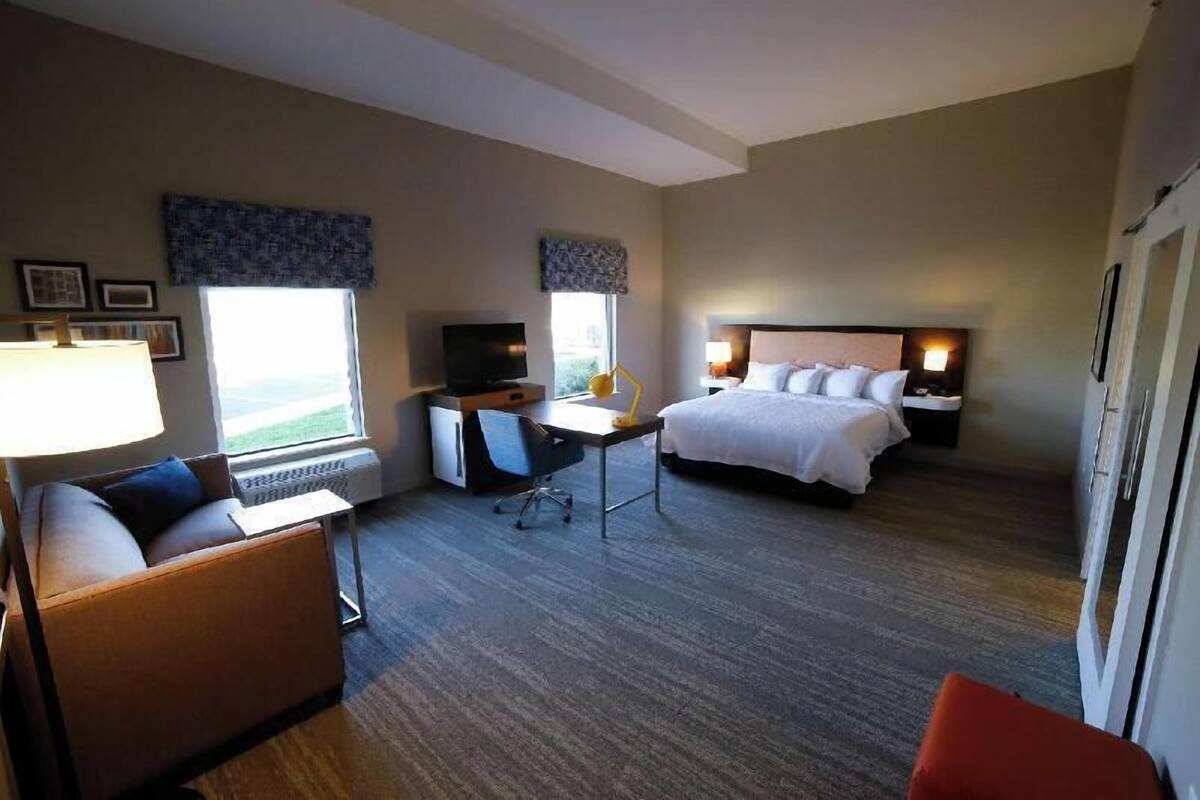 Ein Hotelzimmer mit Bett, Schreibtisch, Stuhl und Blick ins Freie.