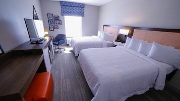 Une chambre d’hôtel avec deux lits, un bureau, une chaise, une télévision et une fenêtre donnant sur un beau paysage.