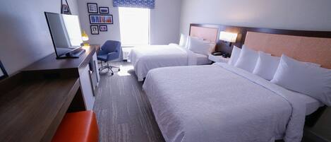 A hotel room with two beds, a desk, a chair, a TV, and a window with a view.