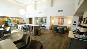Un hall d’hôtel comprenant un comptoir d’accueil, un espace salon et une cheminée.
