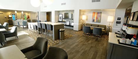 Vestíbulo de hotel con mostrador de recepción, zona de estar y chimenea.