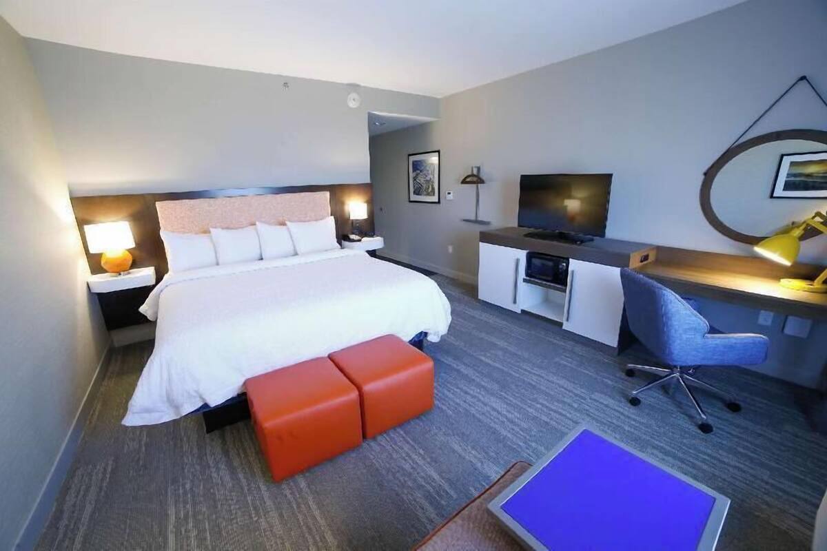 Ein Hotelzimmer mit Bett, Schreibtisch, Stuhl und Fernseher.