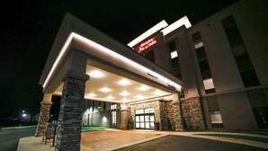 L’entrée d’un hôtel, avec une façade en pierre, un éclairage décoratif et un espace extérieur abrité doté de sièges.