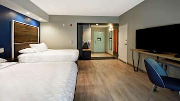 A hotel room with two beds, a desk with a flat-screen TV, and a chair.