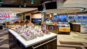 A hotel lobby with a buffet area, seating, and a bar.