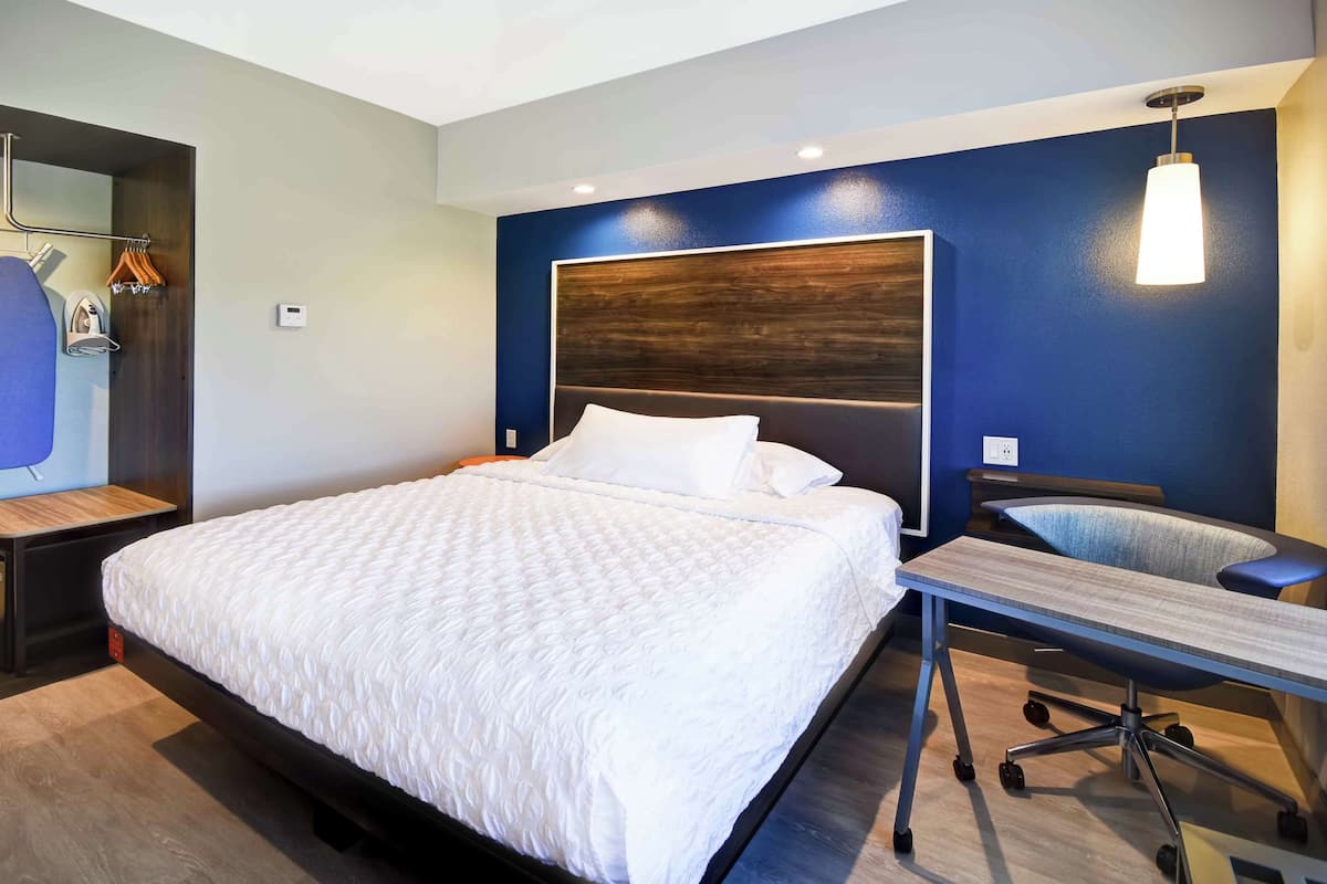 Una habitación de hotel moderna con una cama grande, un escritorio y una silla.