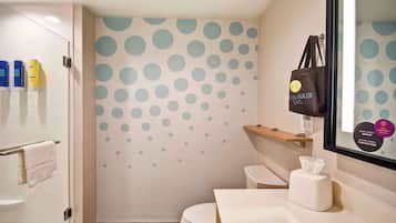 A bathroom with a toilet, sink, and a mirror. There are toiletries on the wall and a bag hanging on the mirror.