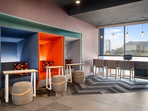 A modern interior with a seating area, tables, and a large window offering a view. - Tru By Hilton Lake Charles (Lake Charles)