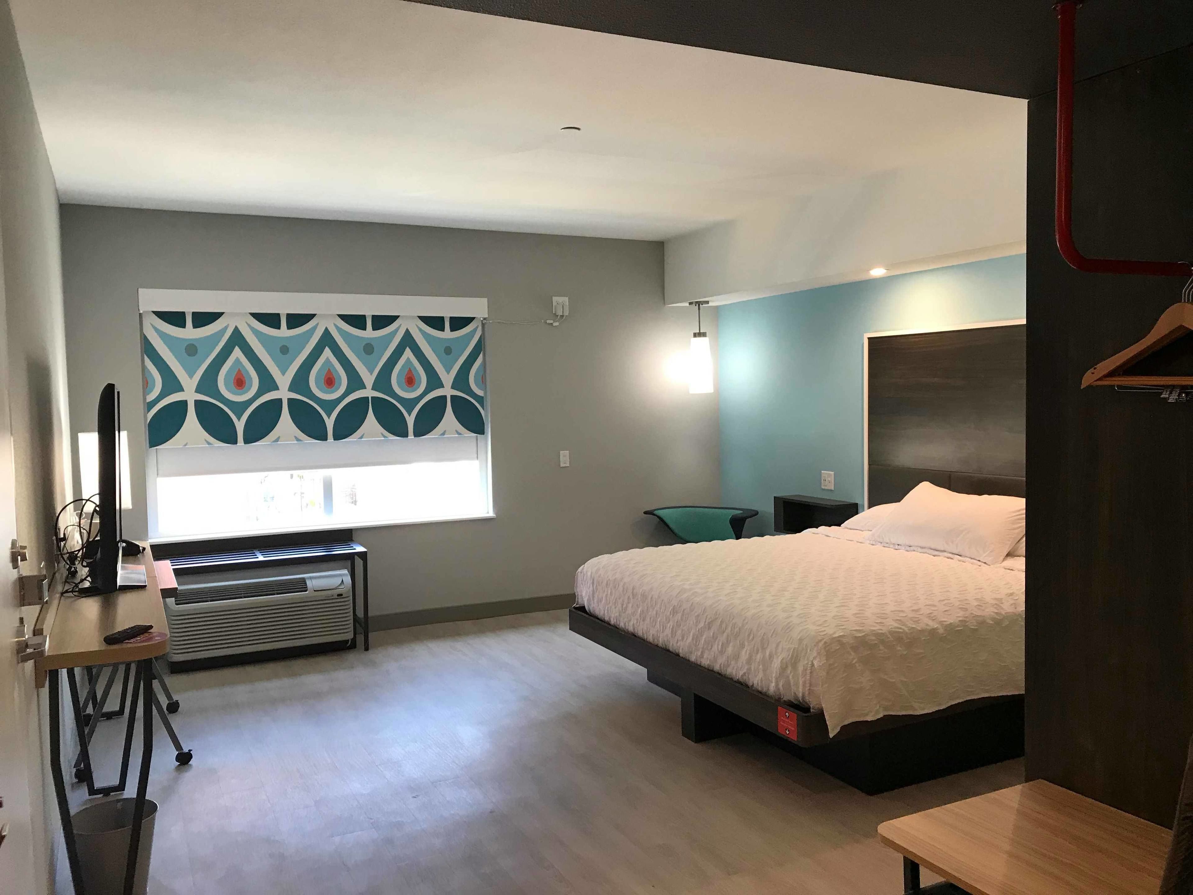 A modern bedroom with a bed, bedside table, and a desk with a chair.