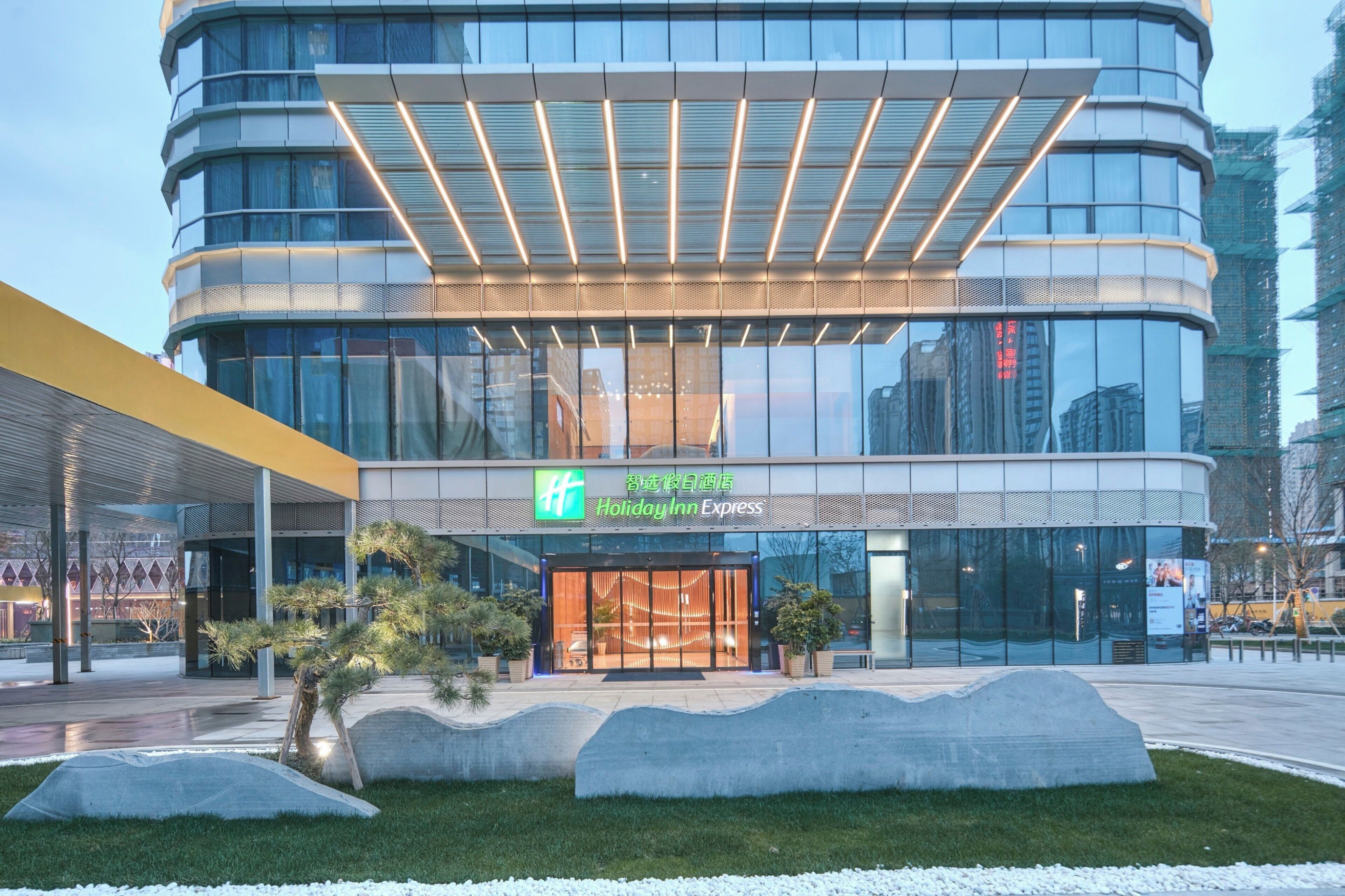 A modern hotel with a curved facade, large glass windows, and a prominent entrance.