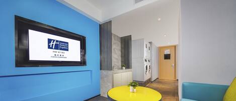 A modern hotel lobby with a blue wall, a yellow table, and a blue sofa.
