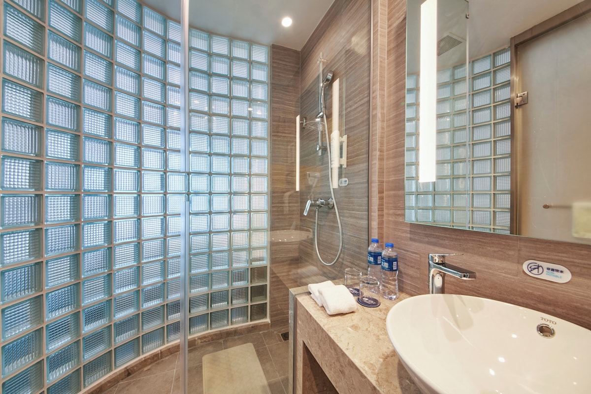 Une salle de bain moderne avec une douche à parois de verre, un lavabo et un miroir.