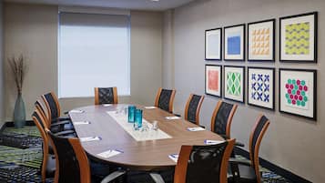 Un salón de conferencias con una larga mesa, sillas y obras de arte enmarcadas en la pared.